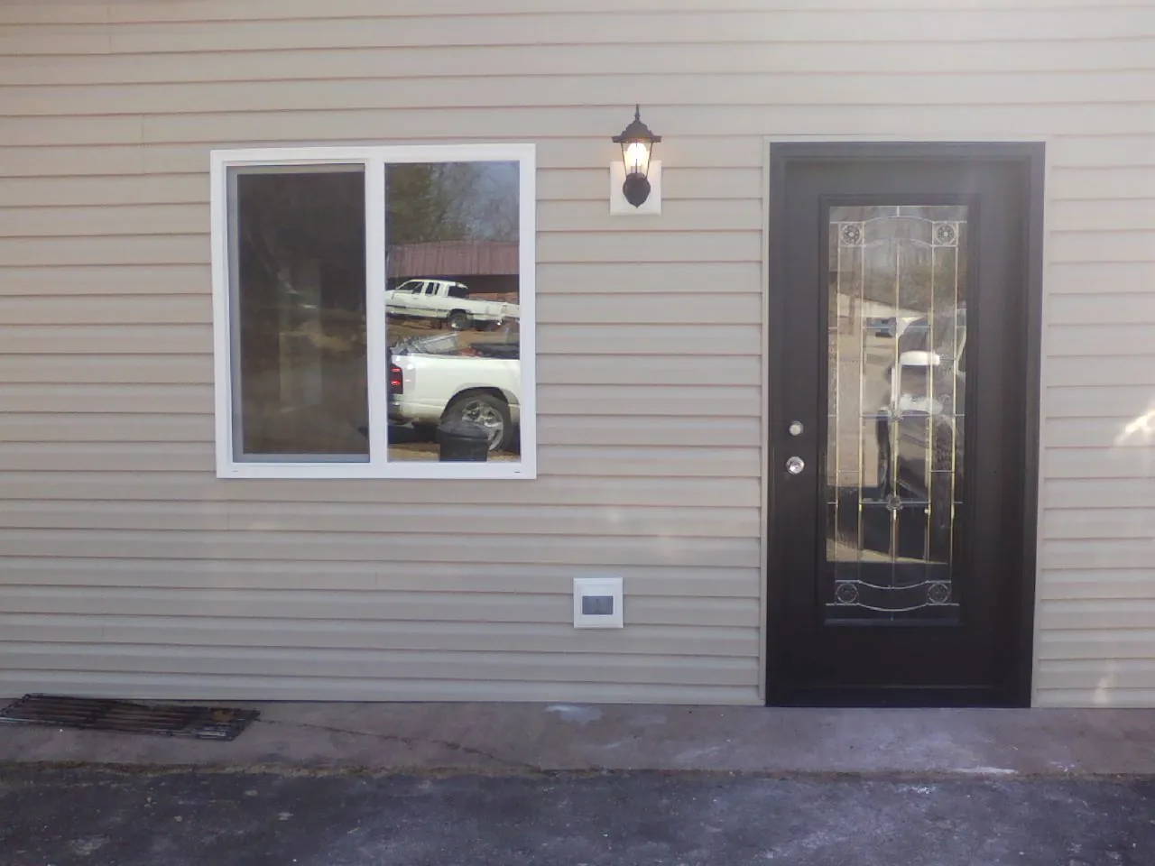 New siding, window and entry door on the side of an addition in Greenlawn