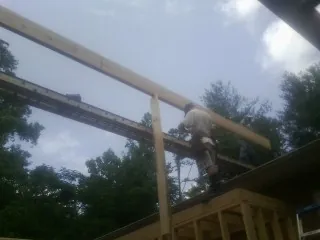 Carpenter setting a ridge beam over a new addition frame — Ice Dam Removal by Roofing Brothers in Greenlawn