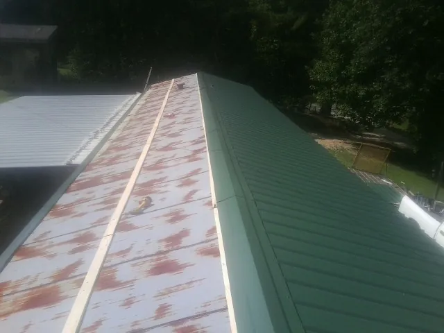 Old rusted panels beside newly installed green metal roofing — Wind Damage Roof Repair by Roofing Brothers in Greenlawn