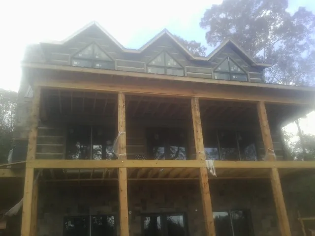 Dormers and porch framing on a large log home under construction — Roof Coating work by our crew in Greenlawn