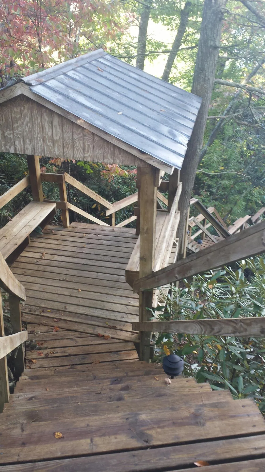 Metal roofed shelter over wooden steps on a wooded walkway — Skylight Repair & Installation work by our crew in Greenlawn
