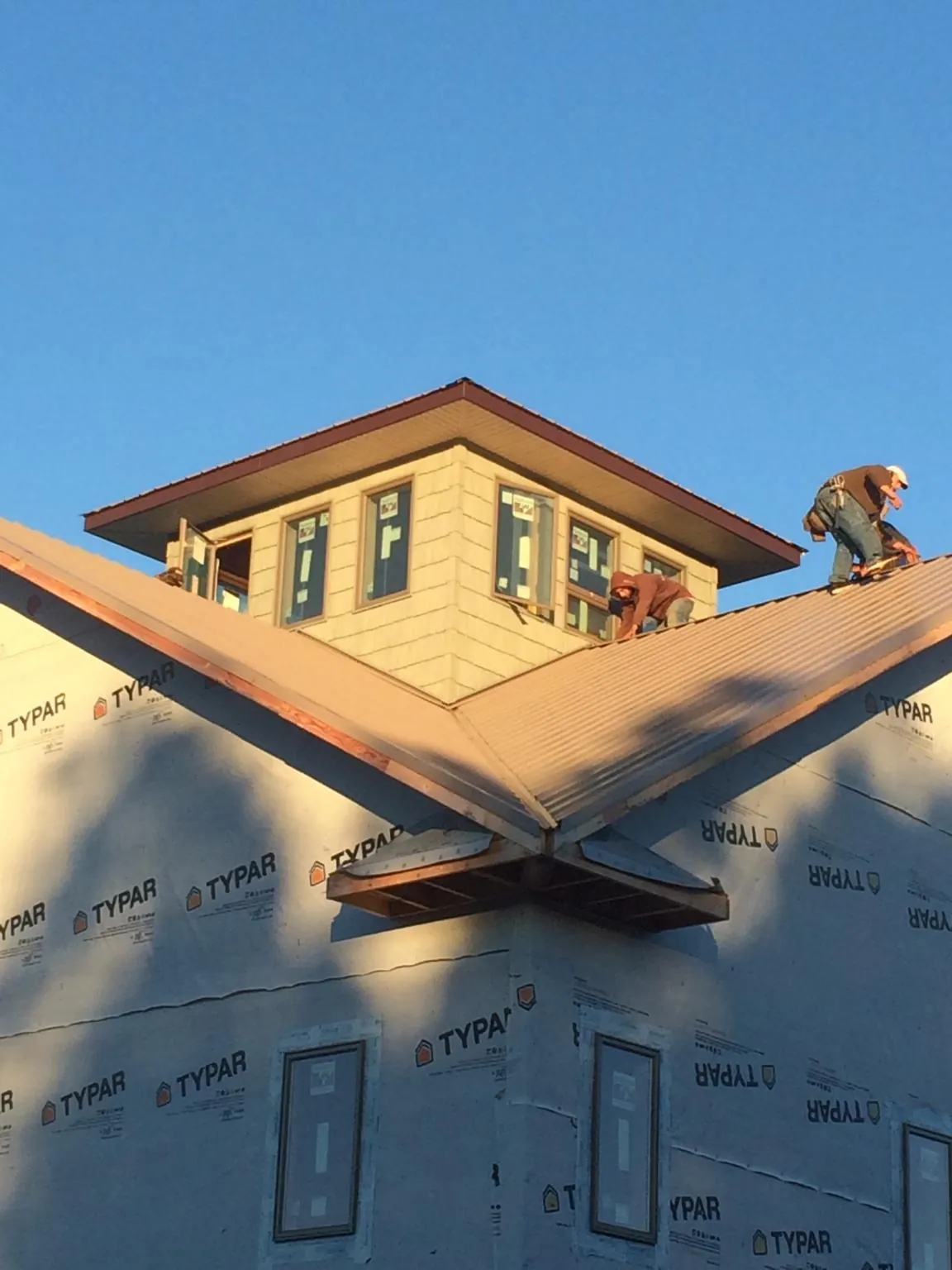 Roofers working around a rooftop cupola on a new metal roof at sunset — Roof Waterproofing in Greenlawn by Roofing Brothers